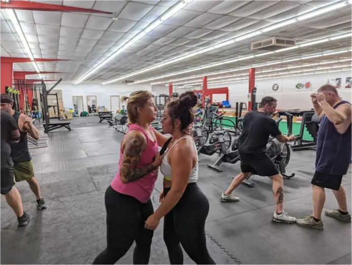 A Lashley trainer coaching a member through a lift on the gym floor